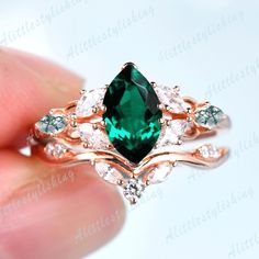 a green ring with white diamonds on it's sides and an emerald stone in the middle