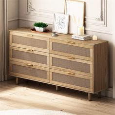 a wooden dresser with two pictures on top and a potted plant sitting on top