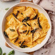 a white bowl filled with ravioli and sage