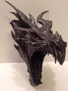 a close up of a metal mask on a white surface with a black dragon's head