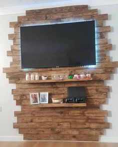 a flat screen tv mounted to the side of a wooden wall with shelves below it