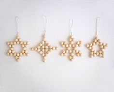 three wooden ornaments hanging from strings on a white surface with one ornament in the shape of a snowflake