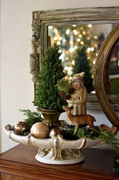 a small christmas tree is on top of a table with ornaments and a mirror in the background