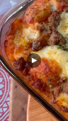 a casserole dish with meat and cheese in it sitting on a wooden table