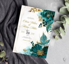 a wedding card with flowers and leaves on it next to some greenery in the background