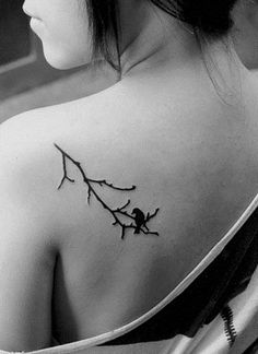 the back of a woman's shoulder with a branch tattoo on her upper arm