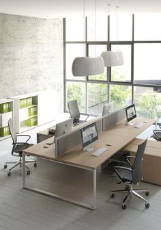 an office with multiple desks and chairs in front of large windows overlooking the city