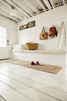 a room with white walls and flooring, two purses hanging on the wall