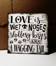 a wooden sign that says love is wet noses, slivery kisses and a wagging tail