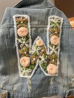 an embroidered jacket with the letter k on it's back and flowers in the middle