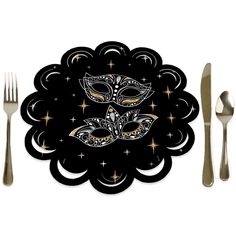 a table setting with silverware, forks and a mask on the top of it