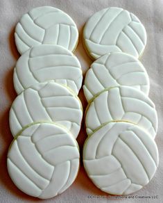 four cookies with white icing are arranged in the shape of volleyball balls