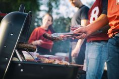 people are grilling hot dogs and sausages on an outdoor grill