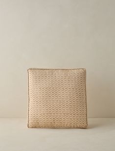 a beige and white pillow sitting on top of a table