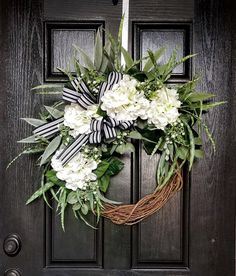 a wreath with white flowers and greenery is hanging on the front door to say, the red rustic rose