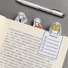 an open book with stickers on it next to a pen and paper clippings