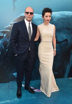 a man and woman standing next to each other on a blue carpet in front of a movie poster