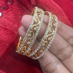 "*  Handcrafted Gold Plated 2 Bangle Set. Sold as a set.   * Bangles with high quality CZ stones.   * High Quality 22K Gold Plated. Bangles Sizes : 2.4 inches= ( 2.25\" diameter of the inner circle) ; 2.6 inches =  ( 2.42\" diameter of the inner circle); 2.8inches = (2.54\" diameter of the inner circle) The gorgeous gold-plated bangles set best exemplifies the careful craftsmanship done on it -- specially picked for you by Nemali Jewelry. It has a special tone of elegance attached to it. The intricate handmade design of the bangle/bracelet set gives it a fresh and original look.    Look your best with this elegant-looking bangle/bracelet set from the house of Nemali Jewelry. This set looks elegant at first glance. You can Mix and match or easily pair it up with glass bangles, Thread work b Gold Bangle Bracelet With American Diamonds, Gold American Diamond Bangle Bracelet, Gold Diamond Bangle With Stone Work, Gold Bangle With Intricate Design In Cubic Zirconia, Gold Bangle With Intricate Cubic Zirconia Design, Gold Plated Hand Set Bangle For Anniversary, Dazzling Round Bangle For Festive Occasions, Gold Bangle With Cubic Zirconia Stone Work, Dazzling Festive Bangle