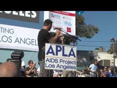 a man standing at a podium in front of a crowd with an appla sign