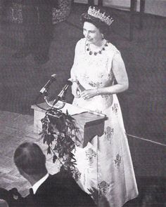 an old photo of queen elizabeth speaking at a podium in front of a man wearing a suit and tie