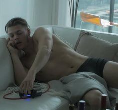 a shirtless man laying on top of a white couch