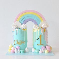 two cakes decorated with rainbows and clouds are sitting on a blue tray next to a white wall