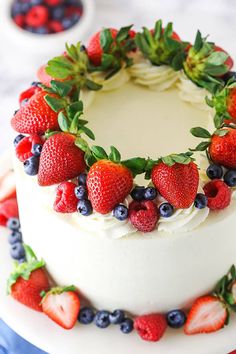 a white cake topped with fresh strawberries and blueberries