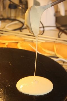 a spoon pouring sauce on top of a black pan