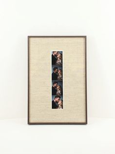 a framed photo hanging on the wall in front of a white wall with three pictures