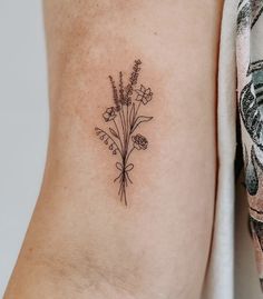 a small flower tattoo on the left side of the arm is shown in black and white