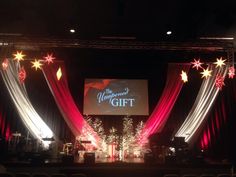 a stage set up with red and white draping, decorated with christmas lights