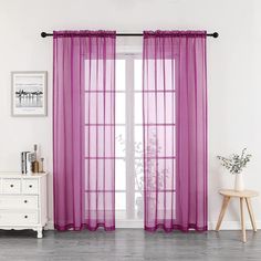 a living room with white walls and purple curtains