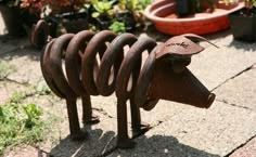 a metal animal sculpture sitting on top of a cement ground next to potted plants