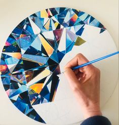 a person is drawing on a piece of paper with a blue pencil and it looks like a mosaic