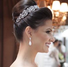 a woman wearing a tiara and smiling at someone in the background with chandelier