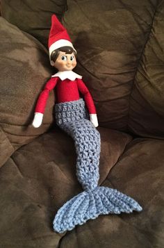 an elf is sitting on the couch with a crocheted mermaid tail and hat