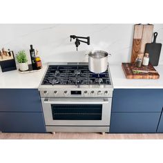 a stove top oven sitting inside of a kitchen next to a cutting board and utensils