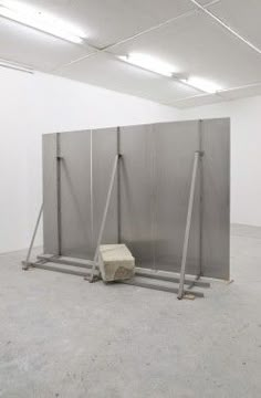 an empty room with three partitions and a stone block on the ground in front of it