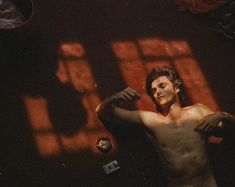 a shirtless man standing in front of a window with his arm up and fist raised