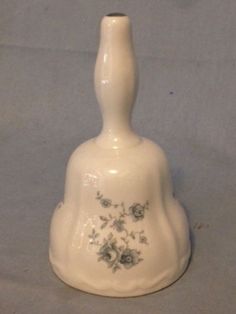 a white vase with flowers painted on the top and bottom, sitting on a gray surface