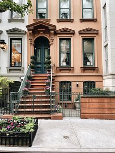 an apartment building with stairs leading up to the front door and flowers on the steps