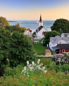 an aerial view of a small town by the water with boats in the bay behind it