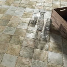 an empty wooden box sitting on the ground next to some vases and bottles in front of it