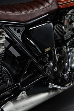 a close up of a motorcycle on a black background with a brown leather seat and backrest