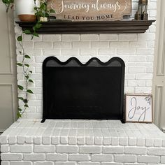 a white brick fireplace with a sign and potted plant on it's mantle