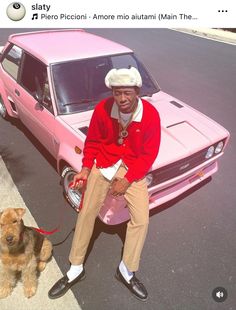 a man sitting on the hood of a pink car next to a brown and tan dog