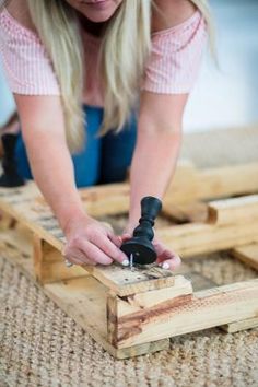 a woman is working on some wood planks with a drill and screwdriver