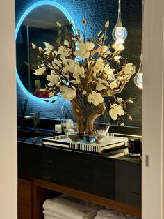 a vase filled with flowers sitting on top of a bathroom counter next to a mirror