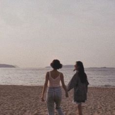 two women walking on the beach holding hands