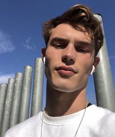 a young man is standing in front of some metal poles and looking at the camera